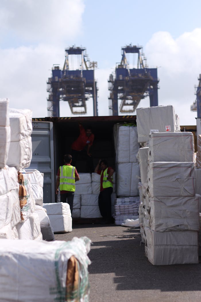 Dock workers loading cargo at Karachi Port with visible cranes and containers.